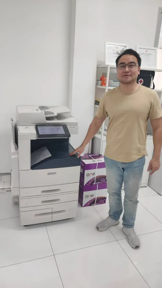 ลูกค้ายืนข้างเครื่องถ่ายเอกสาร Xerox พร้อมกระดาษสำนักงาน
